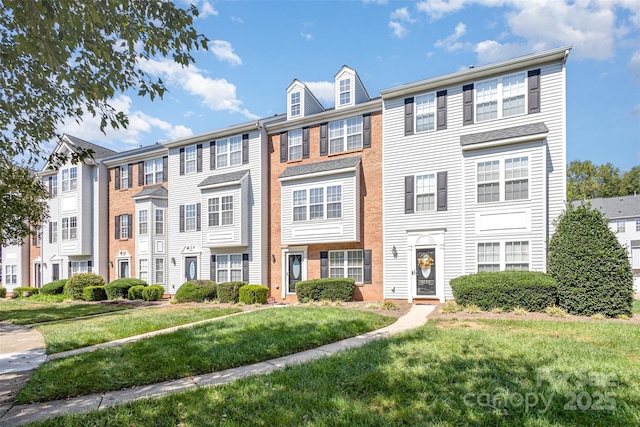 multi unit property with brick siding and a front yard