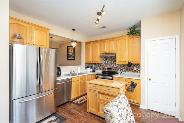 kitchen featuring under cabinet range hood, a sink, light countertops, appliances with stainless steel finishes, and decorative light fixtures