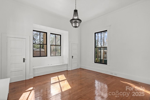 spare room featuring hardwood / wood-style floors, crown molding, and a wealth of natural light