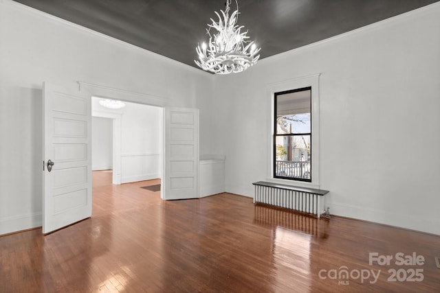 unfurnished room with hardwood / wood-style flooring, ornamental molding, a chandelier, and radiator heating unit