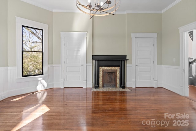 unfurnished living room featuring a chandelier, wood-type flooring, and ornamental molding