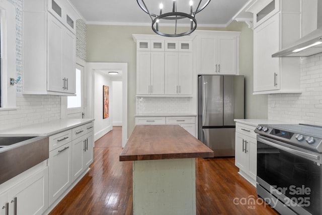 kitchen featuring white cabinetry, stainless steel appliances, a center island, wood counters, and wall chimney range hood