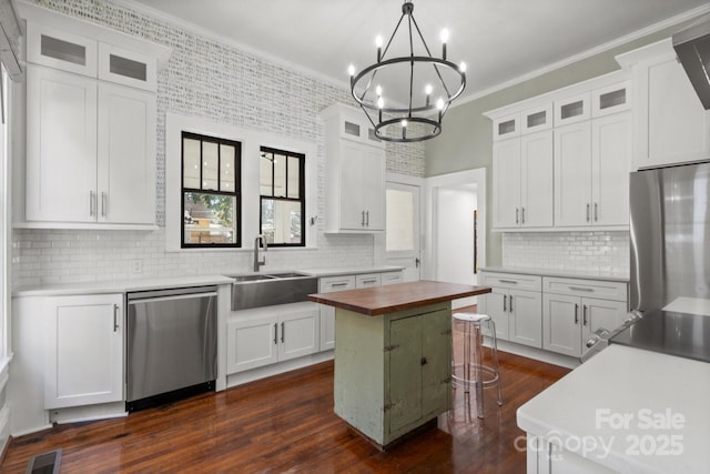 kitchen with stainless steel appliances, white cabinets, decorative light fixtures, a center island, and sink