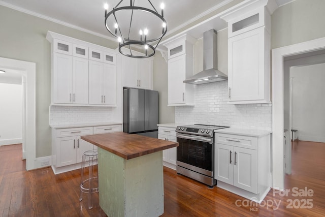 kitchen with appliances with stainless steel finishes, a center island, wooden counters, wall chimney exhaust hood, and white cabinets