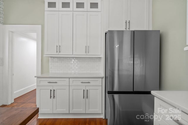 kitchen with white cabinetry, dark hardwood / wood-style flooring, stainless steel fridge, and decorative backsplash