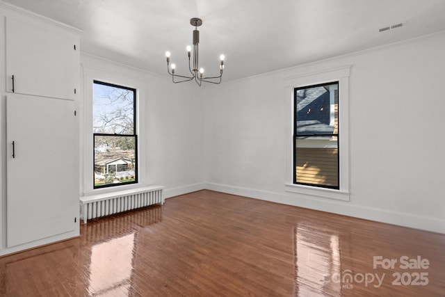 unfurnished room featuring wood-type flooring, radiator, a notable chandelier, and ornamental molding