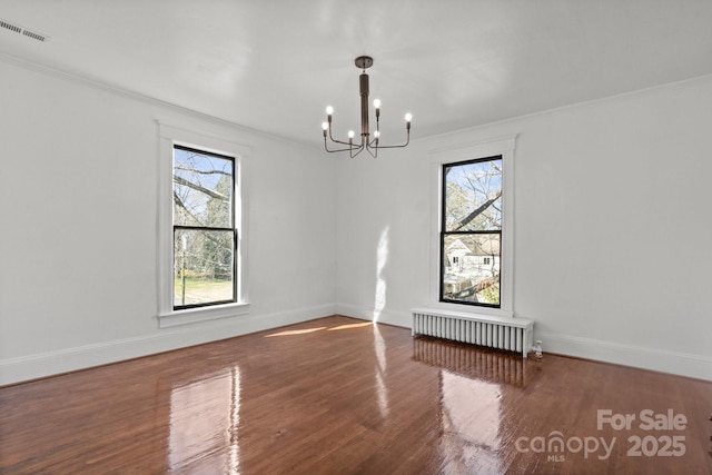 empty room with ornamental molding, dark wood-type flooring, a chandelier, and radiator heating unit