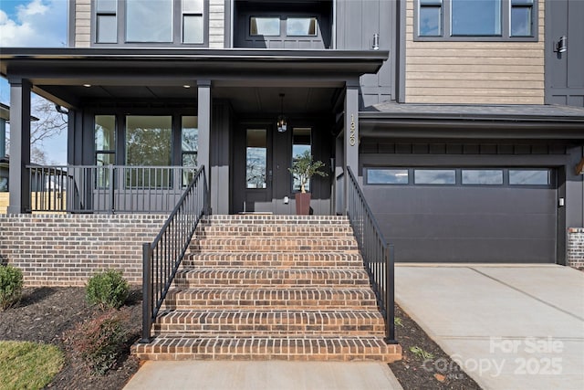 doorway to property with covered porch, concrete driveway, and an attached garage