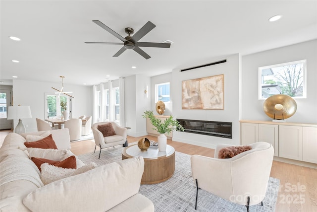 living room with light wood-style floors, recessed lighting, a ceiling fan, and a glass covered fireplace