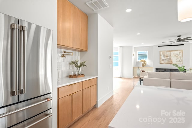 kitchen with light wood-type flooring, freestanding refrigerator, light countertops, and visible vents