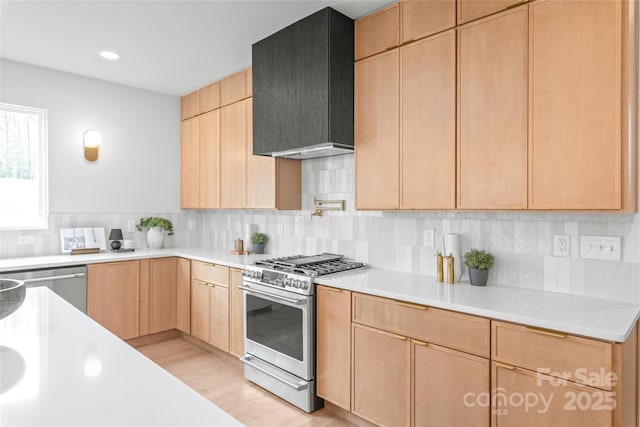 kitchen featuring tasteful backsplash, custom range hood, appliances with stainless steel finishes, light countertops, and light brown cabinetry