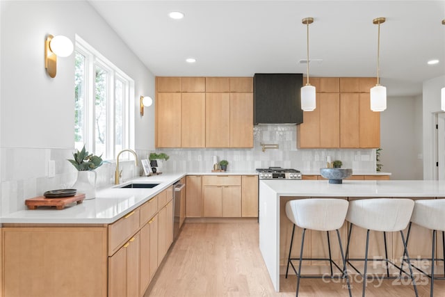 kitchen featuring custom exhaust hood, light countertops, light brown cabinetry, a sink, and a kitchen breakfast bar