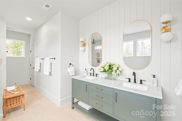 full bathroom with double vanity, a sink, visible vents, and baseboards