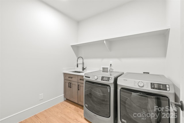 laundry area with cabinet space, light wood-style flooring, washing machine and dryer, a sink, and baseboards