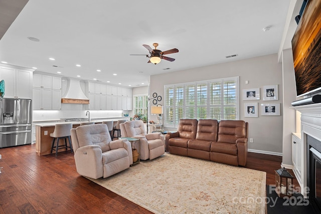 living room with a fireplace with flush hearth, recessed lighting, dark wood-type flooring, and visible vents