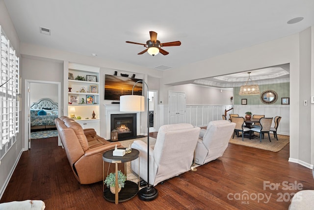 living room with a fireplace with flush hearth, wainscoting, visible vents, and wood finished floors