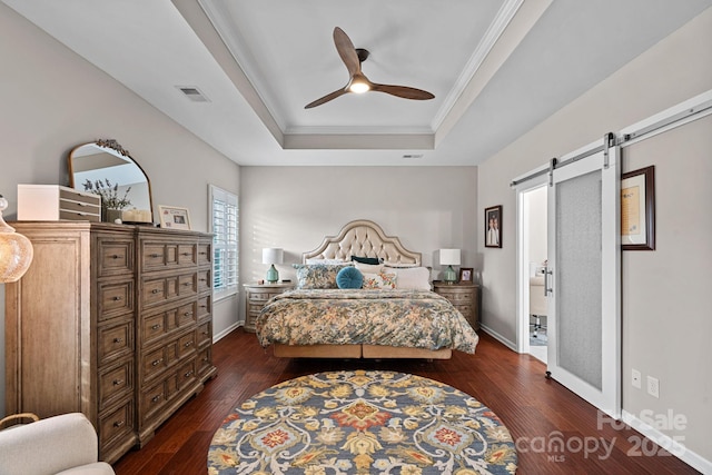 bedroom featuring a barn door, baseboards, visible vents, dark wood-type flooring, and a tray ceiling