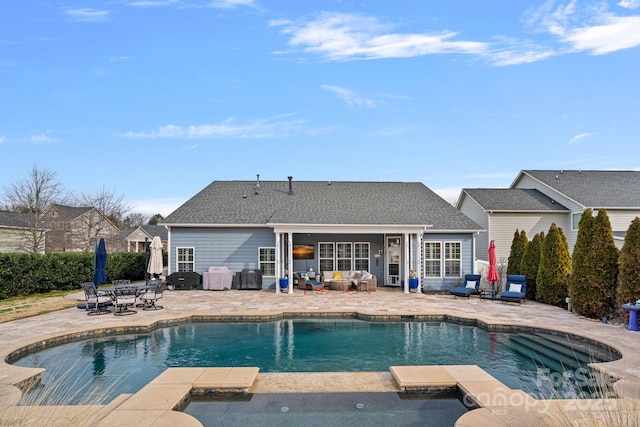 view of swimming pool with outdoor dining space, a pool with connected hot tub, a patio, and an outdoor living space