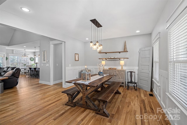 dining space with light hardwood / wood-style flooring and an inviting chandelier