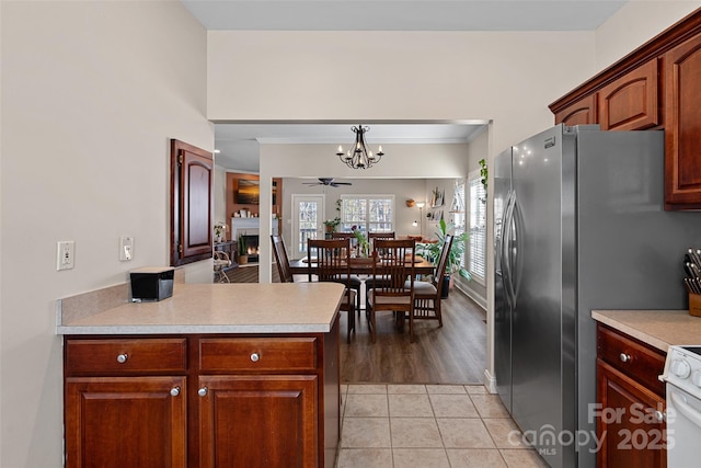 kitchen featuring kitchen peninsula, hanging light fixtures, ornamental molding, light tile patterned flooring, and white stove