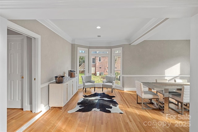 living area with a textured wall, ornamental molding, wood finished floors, and baseboards