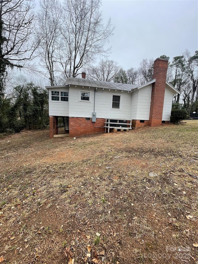 back of property with crawl space and a chimney