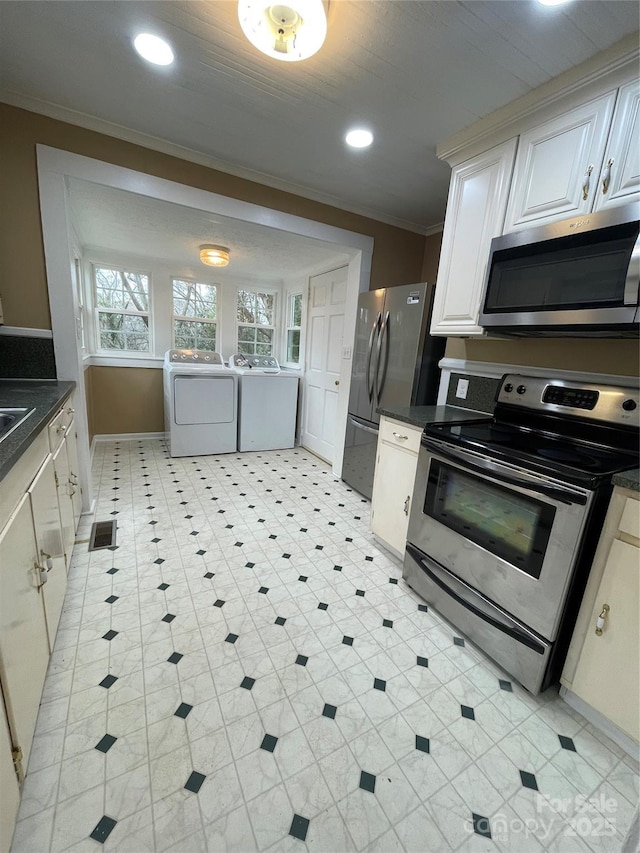 kitchen featuring recessed lighting, ornamental molding, appliances with stainless steel finishes, washer and clothes dryer, and dark countertops