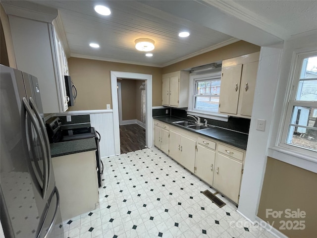 kitchen with stainless steel appliances, dark countertops, visible vents, wainscoting, and a sink