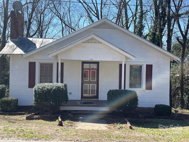 view of front facade with covered porch and a chimney