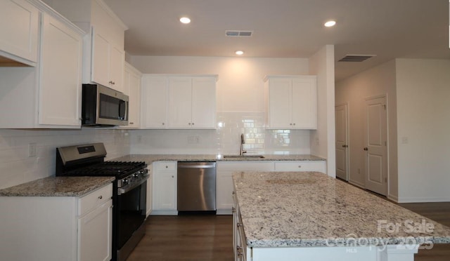 kitchen with stainless steel appliances, visible vents, a sink, and white cabinetry