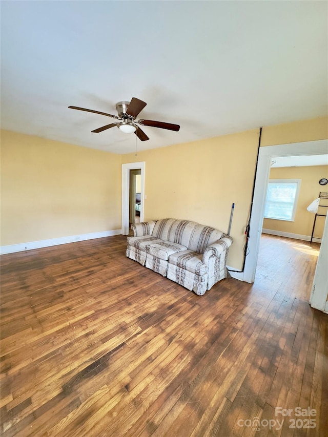 living room with ceiling fan, dark wood-style flooring, and baseboards