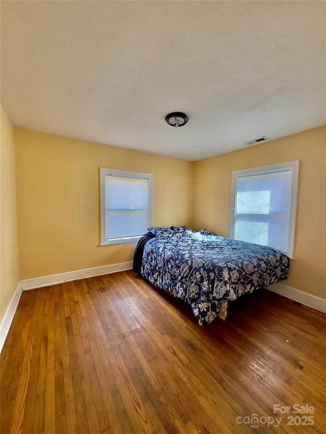 bedroom featuring visible vents, baseboards, and wood finished floors