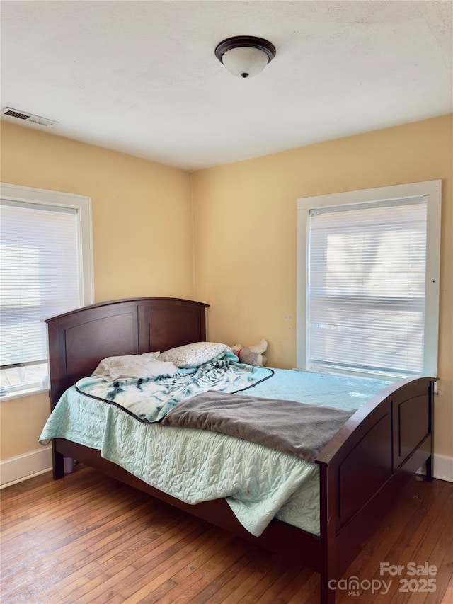 bedroom featuring visible vents, baseboards, and wood finished floors