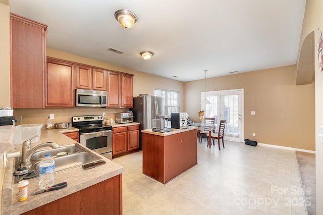 kitchen featuring visible vents, a kitchen island, a sink, stainless steel appliances, and light countertops