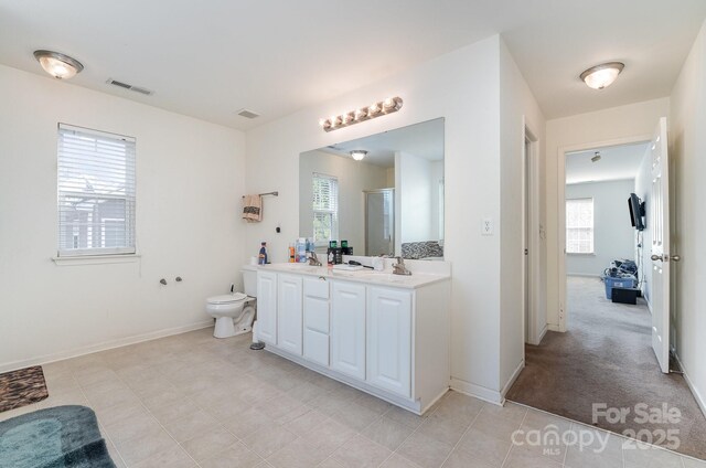 full bath with visible vents, baseboards, double vanity, a stall shower, and toilet