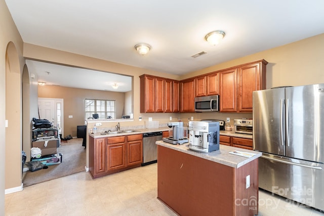 kitchen featuring brown cabinetry, visible vents, a sink, light countertops, and appliances with stainless steel finishes