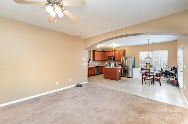 kitchen with brown cabinetry, visible vents, arched walkways, appliances with stainless steel finishes, and open floor plan