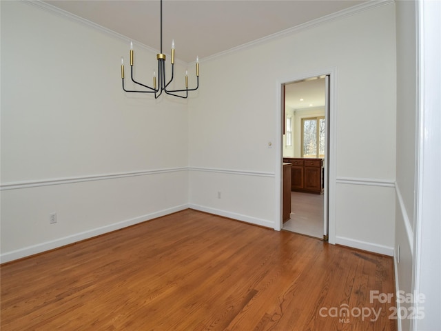 spare room with hardwood / wood-style flooring, crown molding, and a chandelier