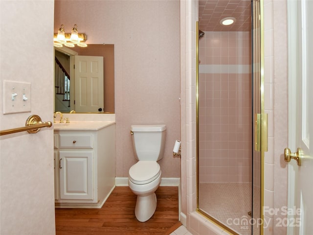 bathroom featuring vanity, a shower with door, toilet, and hardwood / wood-style floors