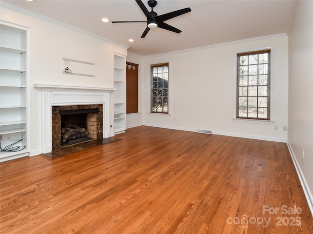 unfurnished living room featuring hardwood / wood-style flooring, a high end fireplace, crown molding, and built in features