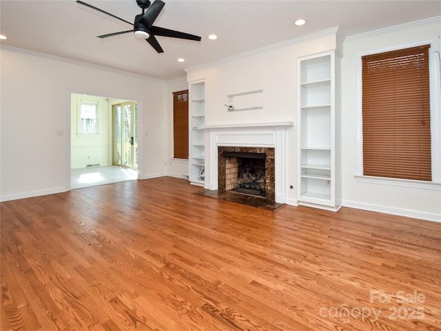 unfurnished living room featuring a fireplace, ornamental molding, light wood-type flooring, and ceiling fan