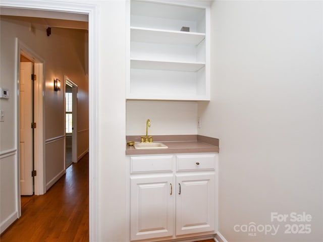 bar with sink, dark wood-type flooring, and white cabinets