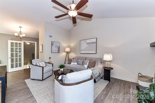 living room featuring wood finished floors, visible vents, baseboards, lofted ceiling, and ceiling fan with notable chandelier