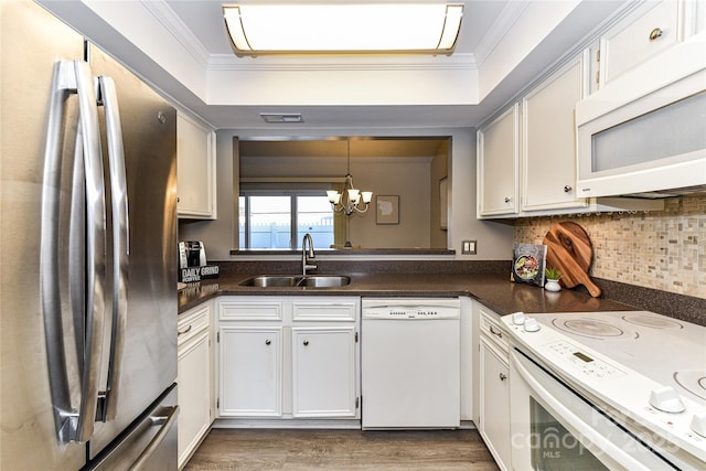 kitchen featuring a sink, white appliances, dark countertops, and crown molding