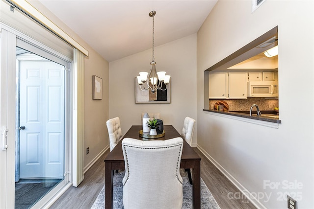 dining space with vaulted ceiling, visible vents, baseboards, and wood finished floors