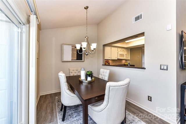 dining room featuring dark wood finished floors, an inviting chandelier, baseboards, and visible vents