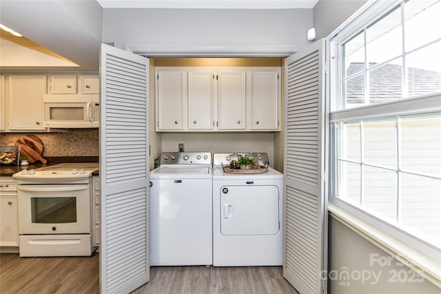 laundry room featuring light wood-style flooring, cabinet space, and washer and clothes dryer