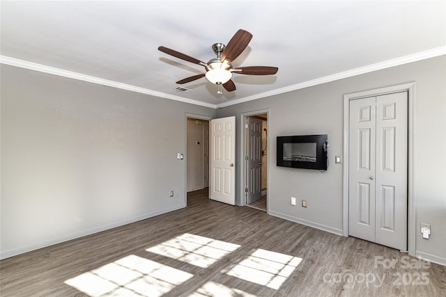 unfurnished bedroom with crown molding, wood finished floors, visible vents, and baseboards