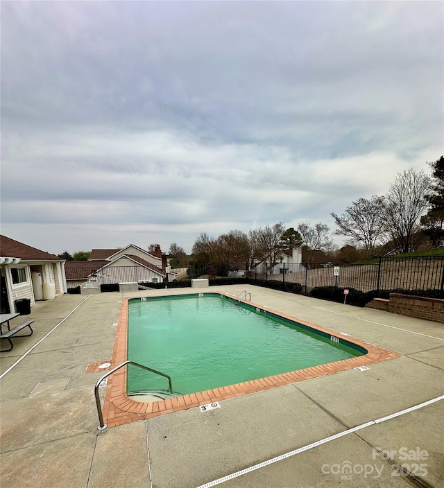 community pool with a patio area and fence