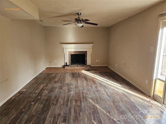 unfurnished living room with hardwood / wood-style floors, a wealth of natural light, a textured ceiling, and a fireplace